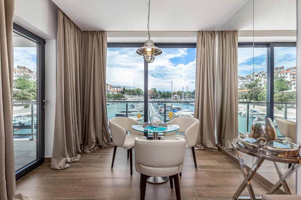 ein Esszimmer mit einem Tisch und Stühlen sowie einem großen Fenster in der Unterkunft Apartments Marina Novi in Novi Vinodolski