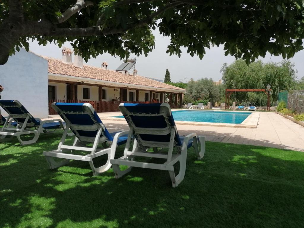 zwei Gartenstühle im Gras in der Nähe eines Pools in der Unterkunft Casas Rurales Noguericas in Archivel