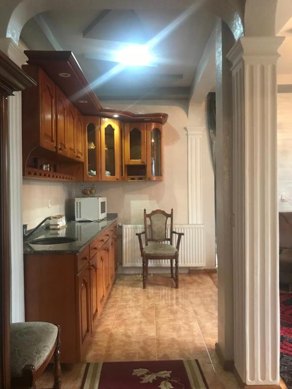 uma cozinha com armários de madeira, uma mesa e uma cadeira em Apartment on Grishashvili 1 em Batumi