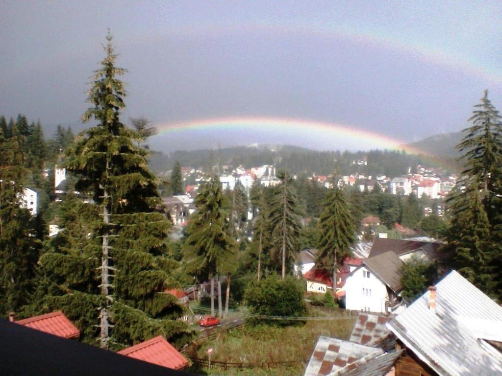 a rainbow in the sky over a town with trees at Apartament 2 cam Predeal in Predeal
