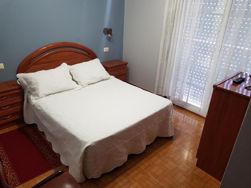 1 dormitorio con 1 cama con sábanas blancas y ventana en Rincón Do Demo, en Nigrán