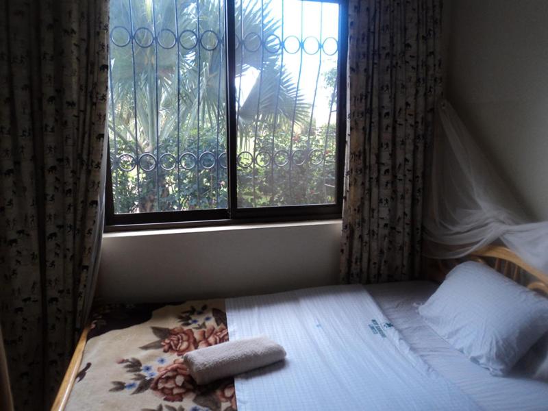 a small bedroom with a bed and a window at Rest Gardens Ltd in Kampala