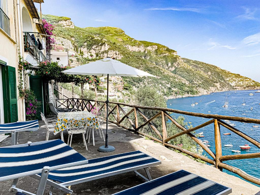 a patio with chairs and an umbrella and the water at Casa Livia in Positano