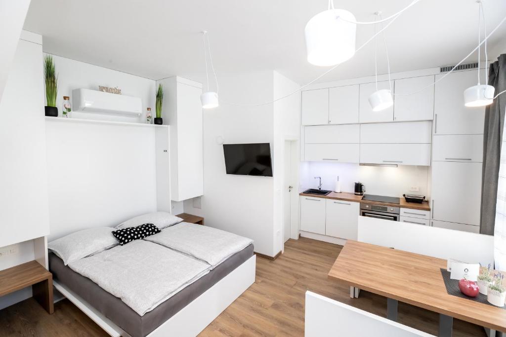 een witte slaapkamer met een bed en een tafel bij Apartma J.E.Ž. in Bohinj