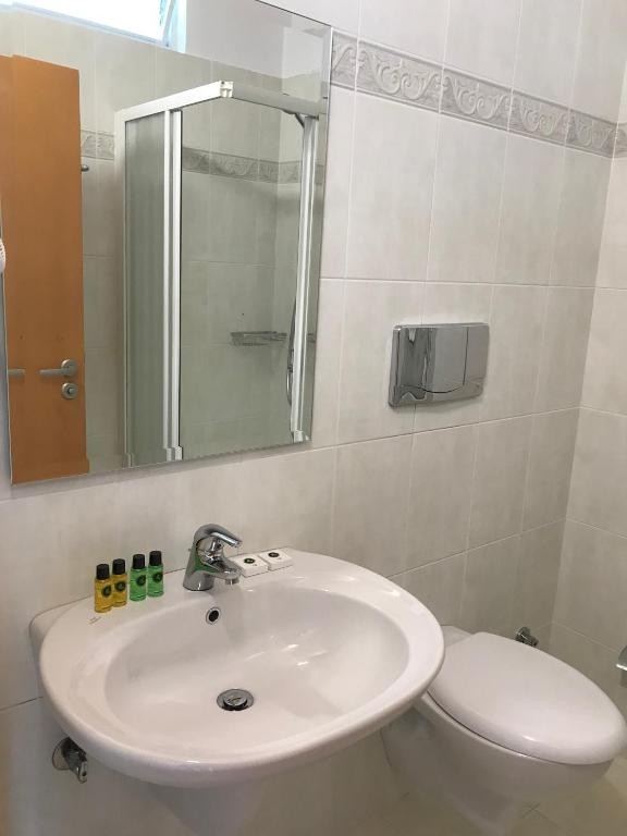 a bathroom with a sink and a toilet and a mirror at Sun N Blue Hotel in Sarandë