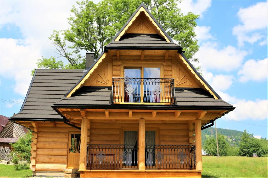 uma cabana de madeira com um telhado de gambrel e uma varanda em Domek w Raju em Kościelisko