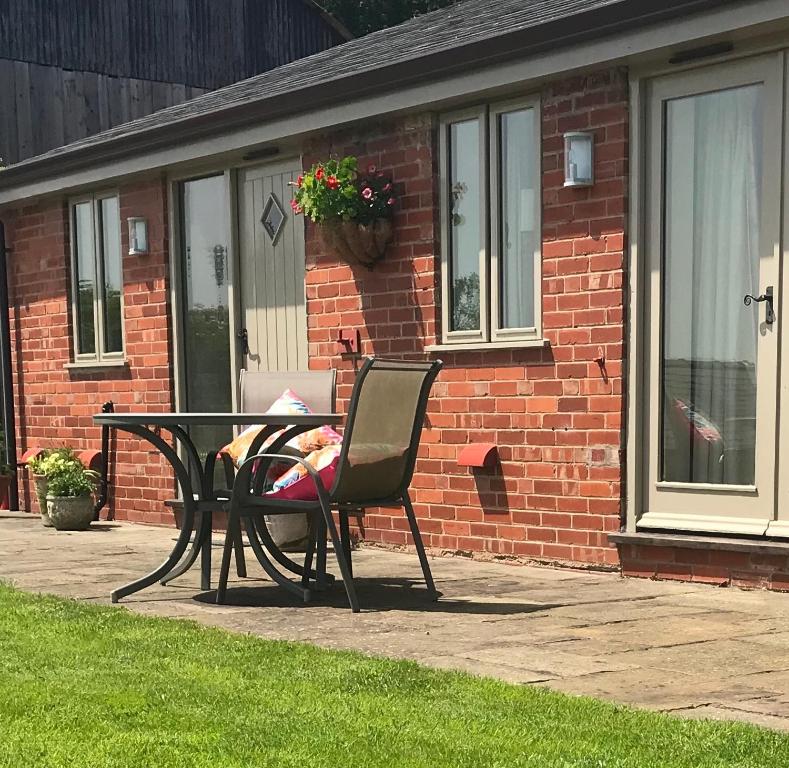 uma mesa e cadeira em frente a uma casa de tijolos em Gaer Fawr Barns em Guilsfield