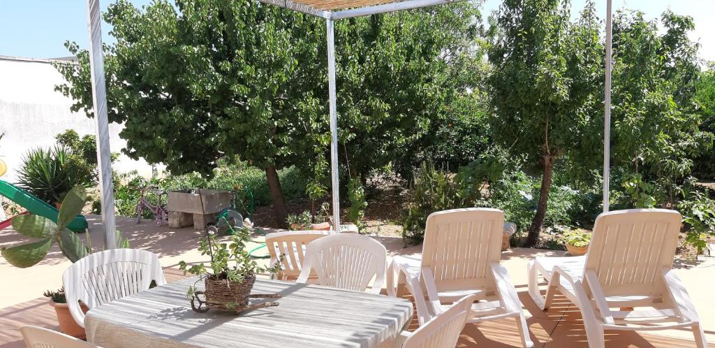 uma mesa com cadeiras brancas e uma mesa com uma planta sobre ela em Da Nonna Cosimina em Casamassella