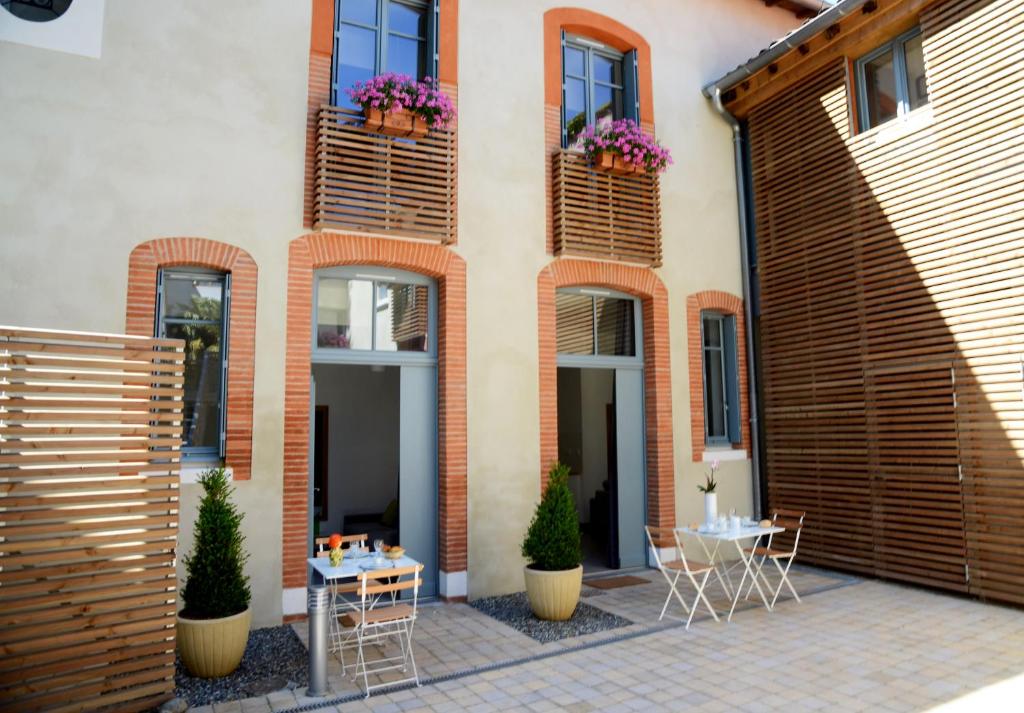 un patio con mesas y sillas frente a un edificio en Le Clos des Salins en Toulouse