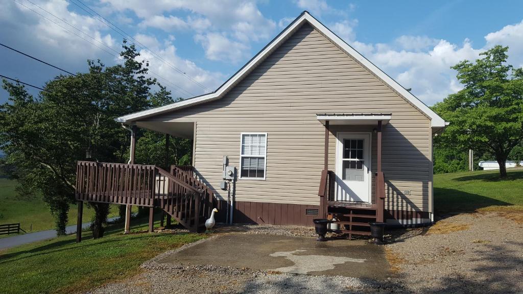 uma pequena casa com um alpendre e um deque em Cabin by the lake em Burnside