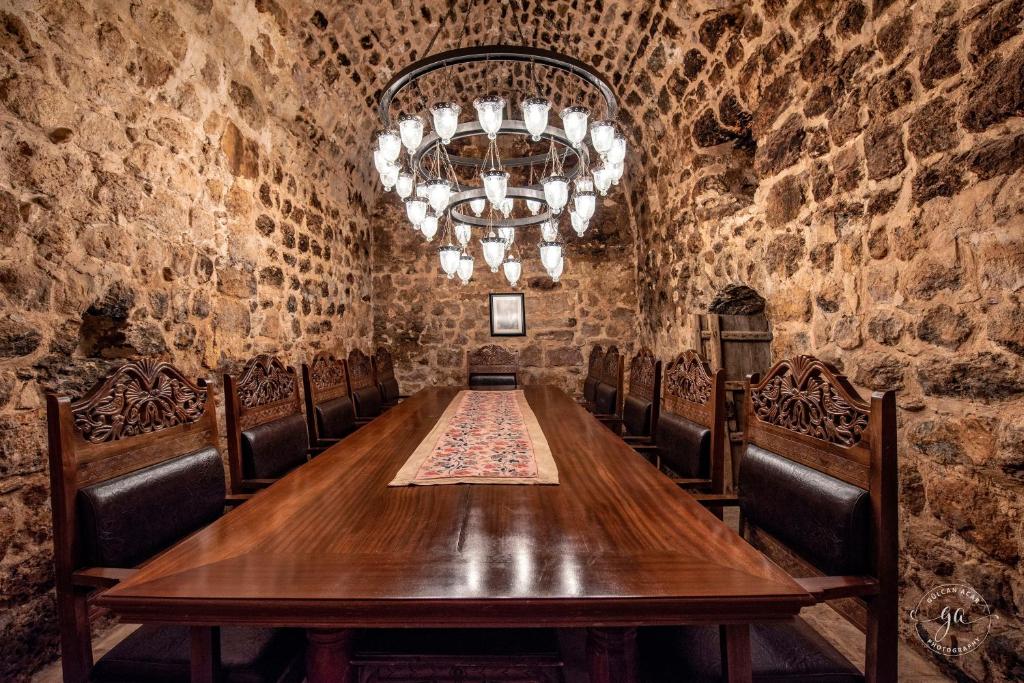 uma sala de jantar com uma mesa e cadeiras e um lustre em Kasr-i Nehroz Hotel em Midyat