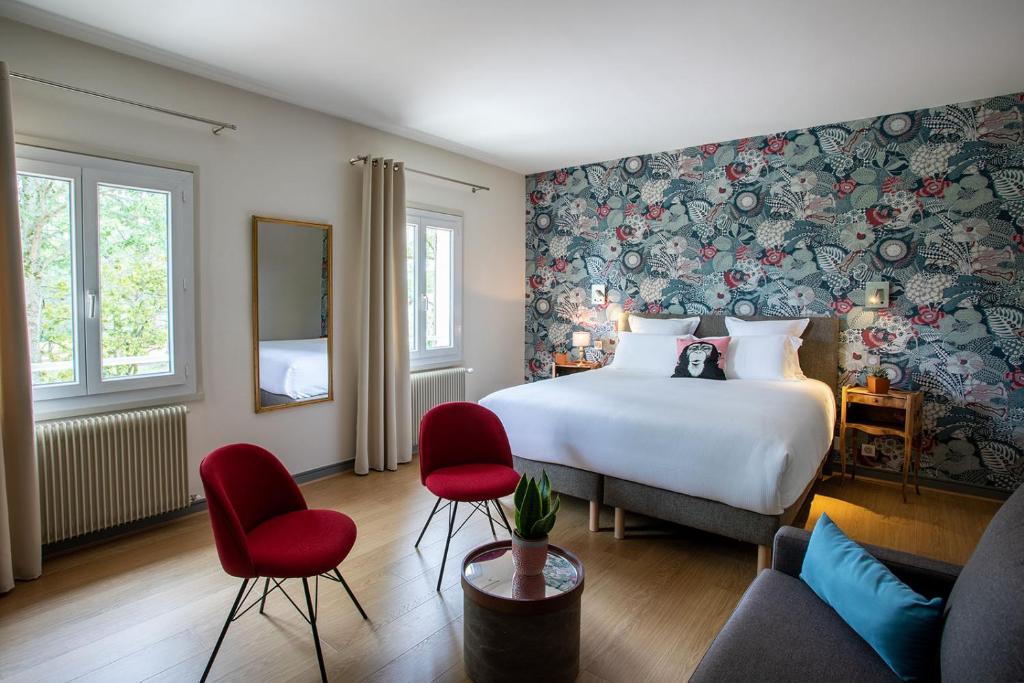 een hotelkamer met een bed en rode stoelen bij Hôtel Restaurant Gastronomique La Huchette in Mâcon