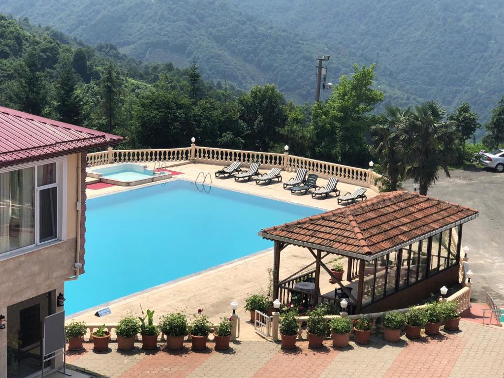 a large swimming pool with a gazebo and chairs at Zarha Mountain Resort in Sürmene