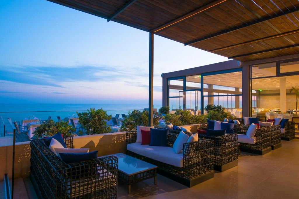 eine Terrasse mit Sofas und Tischen auf dem Dach in der Unterkunft I Resort Beach Hotel & Spa in Stalida