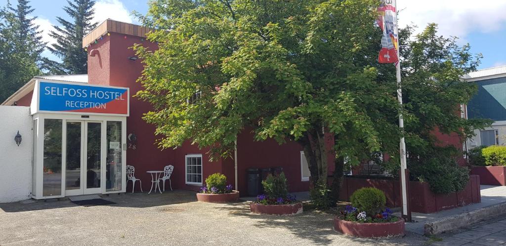 un edificio rojo con un árbol delante de él en Selfoss Hostel, en Selfoss