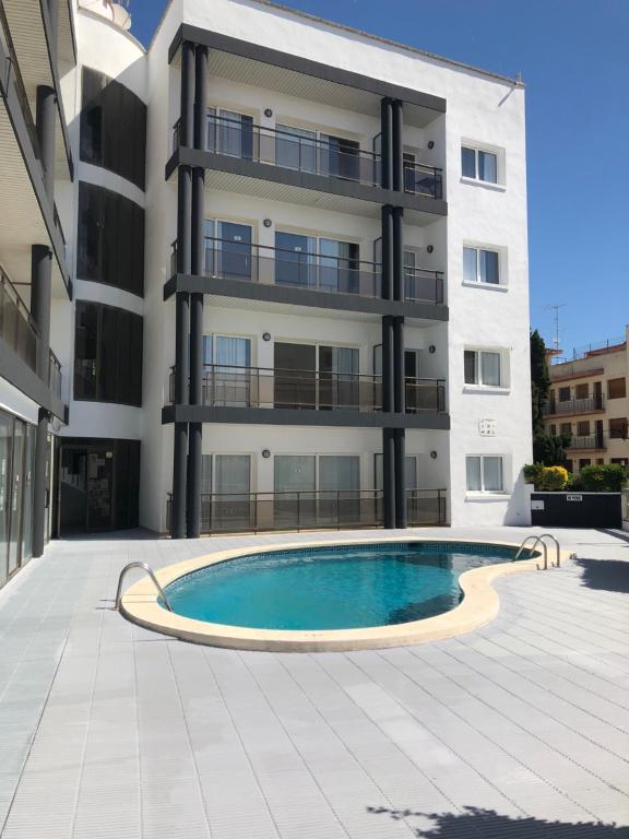 a building with a swimming pool in front of a building at Apartamentos AR Melrose Place in Lloret de Mar