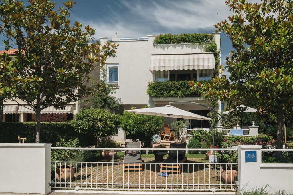 a white building with an umbrella and tables and chairs at Apartments Lucija in Zadar