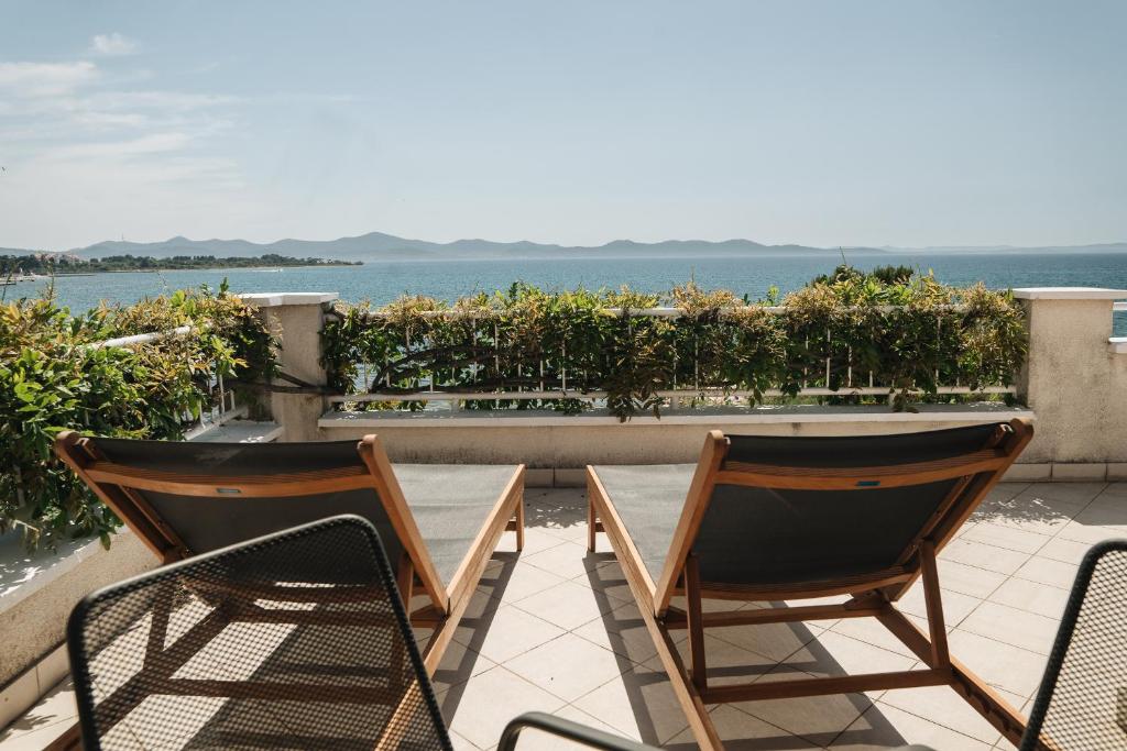 two chairs and a table on a patio with the ocean at Apartments Lucija in Zadar