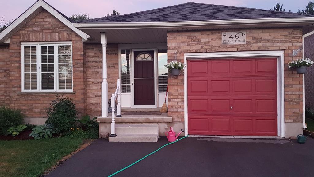 a house with a red garage door with a green hose at Evening Shade in Fergus