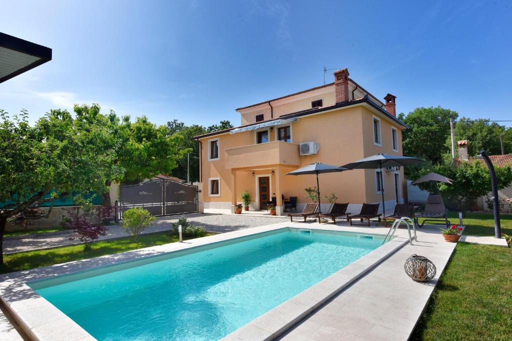 a villa with a swimming pool in front of a house at Villa Aromatica in Vižinada