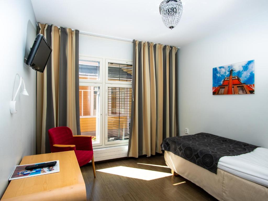 a bedroom with a bed and a desk and a window at Hotel Jahtihovi in Kuopio