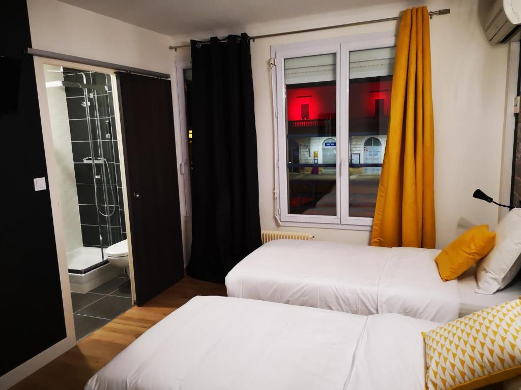 a hotel room with two beds and a window at Hôtel Bar Brasserie L'ESCALE in Bergerac