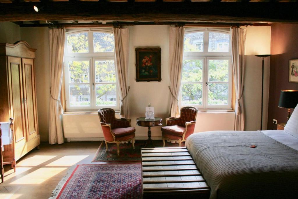 een slaapkamer met een bed en een tafel en ramen bij B&B Au Lion D'or in Maastricht