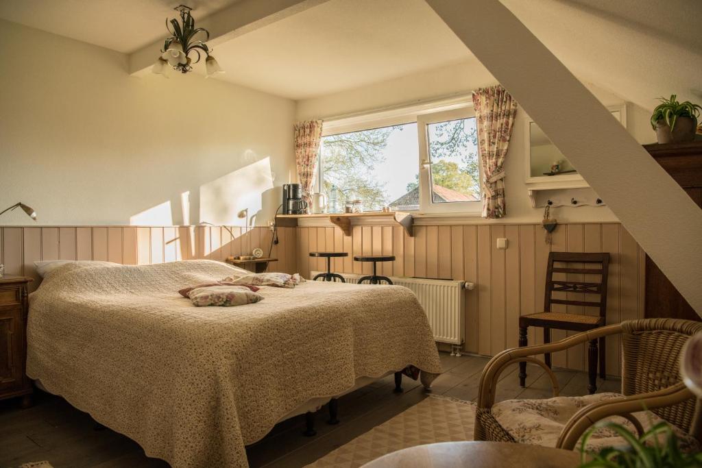 een slaapkamer met een bed en een raam en stoelen bij boerderijkamer Zwanebloem in Onstwedde