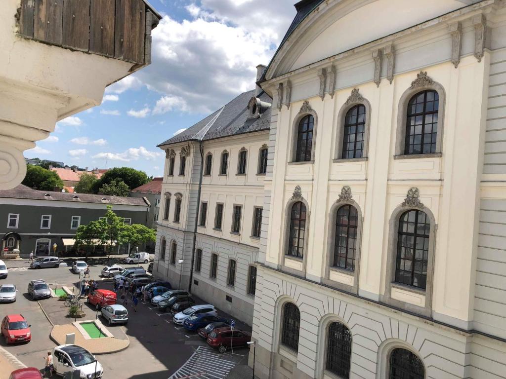 a large building with cars parked in a parking lot at Palace - Belvárosi Apartman Eger in Eger