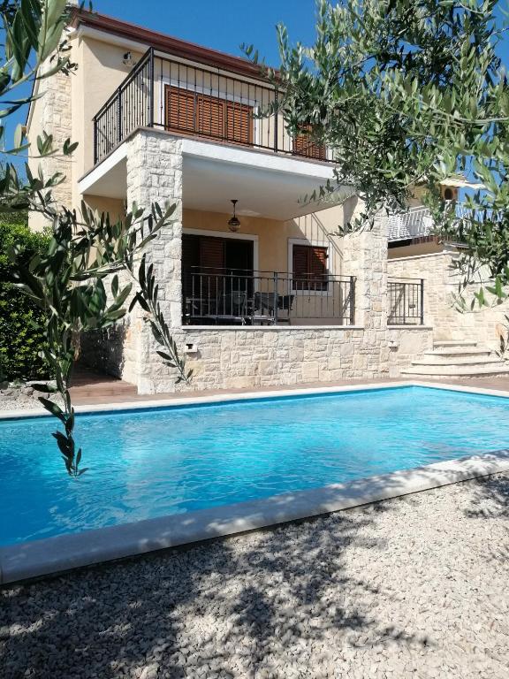 a villa with a swimming pool in front of a house at Casa Emma in Krk