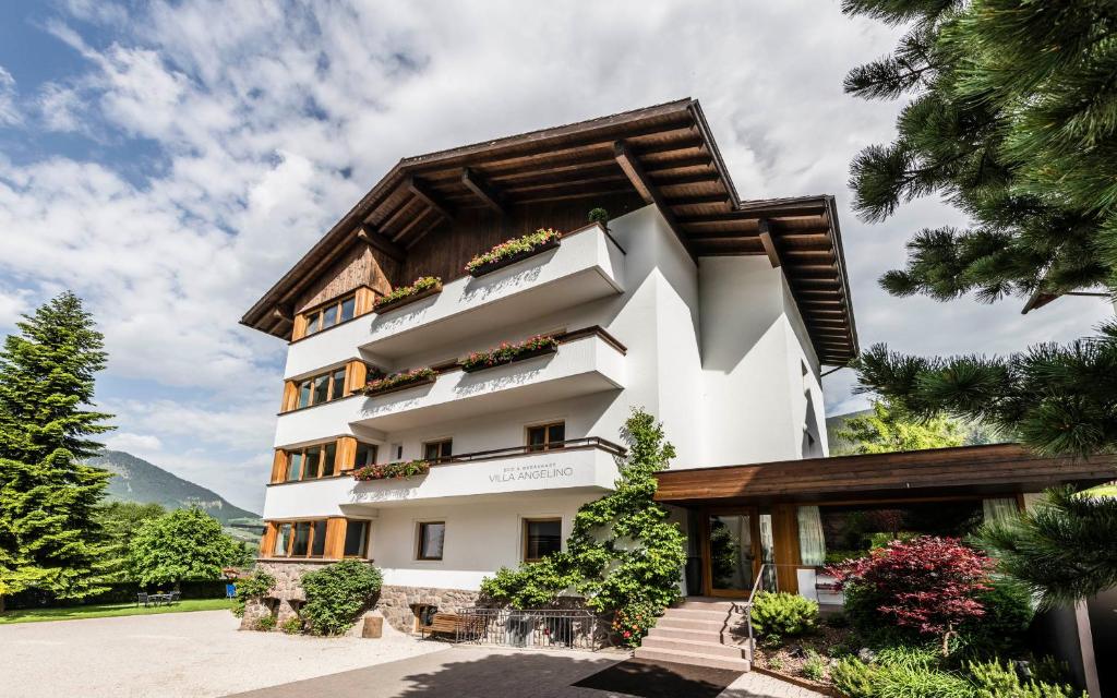 a white building with a wooden roof at B&B Villa Angelino in Ortisei