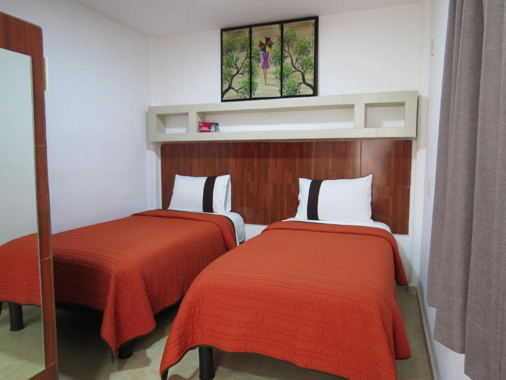 a bedroom with two beds with red sheets and a window at Hotel del Arte y Figura in León