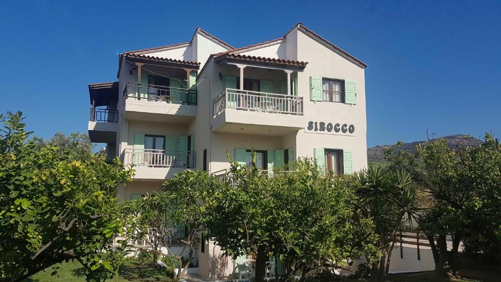 a white building with trees in front of it at Sirocco Apartments in Hersonissos
