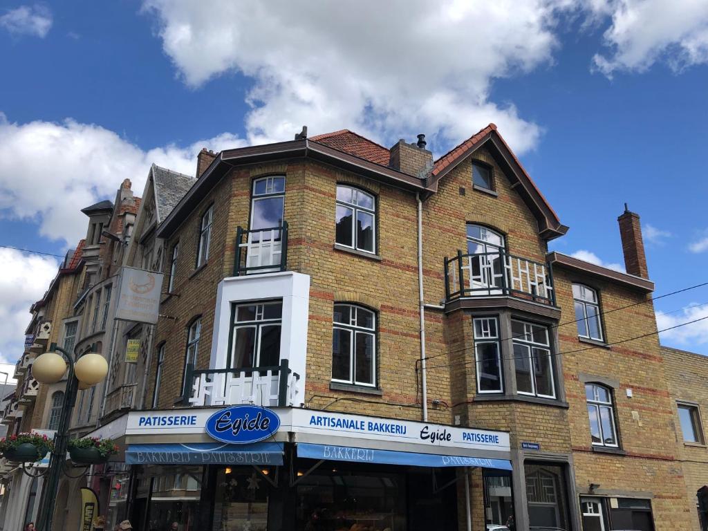 a large brick building on the corner of a street at Le beau coin (belle-etage) in De Panne