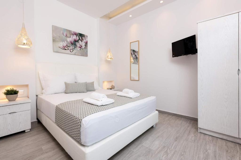 a white bedroom with a large bed and a tv at Polyxeni's Studios in Limenas