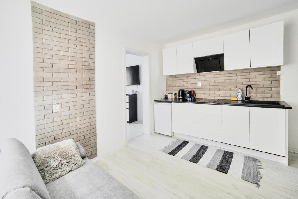 una cocina con armarios blancos y una pared de ladrillo en Apartament Lelewela 8 en Olsztyn