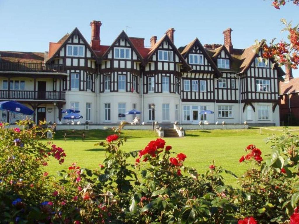 a large building with a green yard with red flowers at Sea Marge Hotel in Overstrand