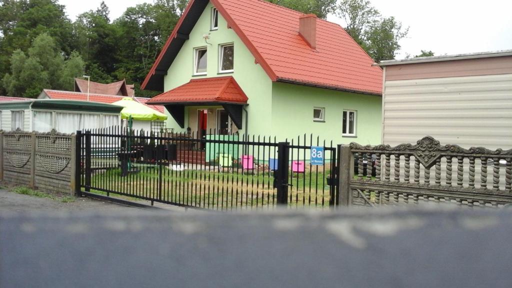 a house with a fence and a house with a red roof at Pokoje Morska in Chłopy
