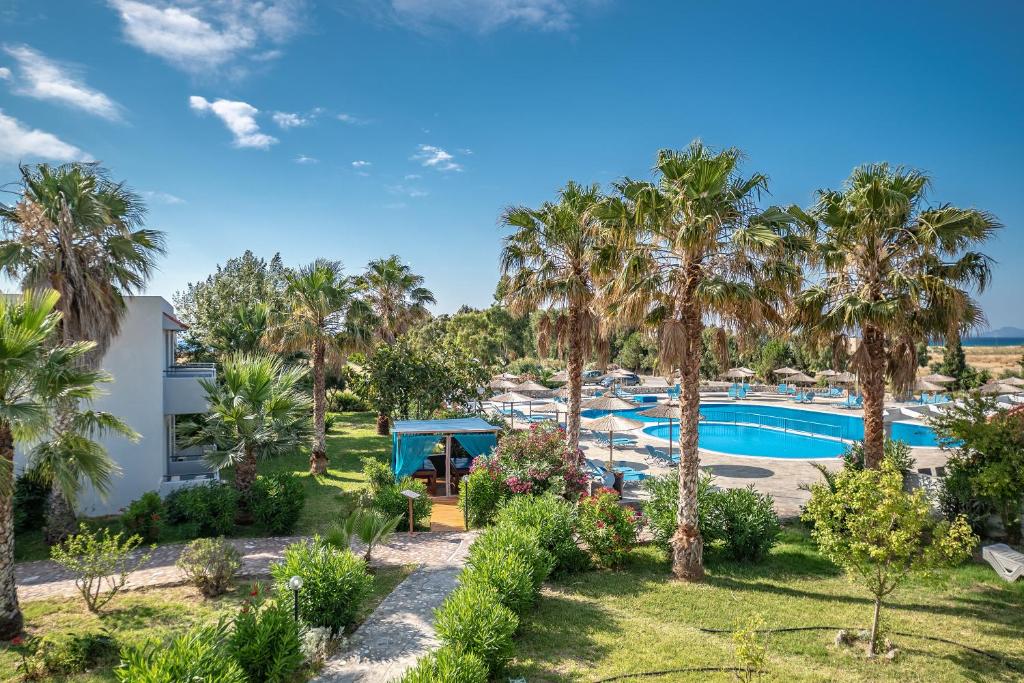 an aerial view of a resort with a pool and palm trees at Evripides Village in Kardamaina