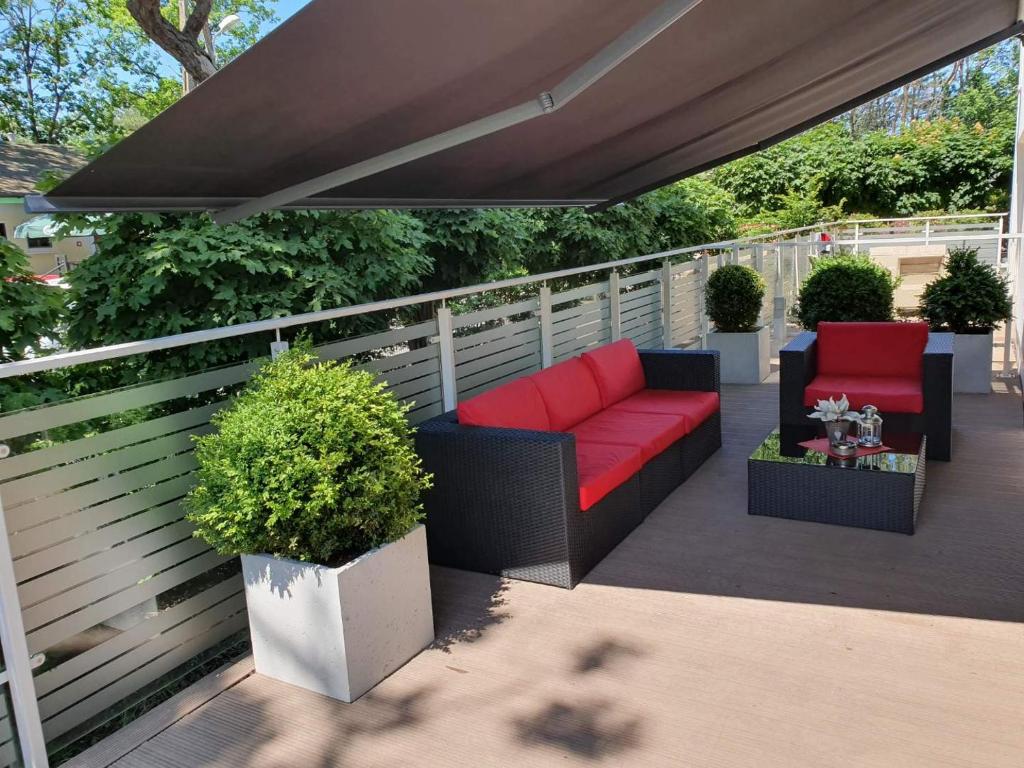 een patio met een rode bank en stoelen onder een luifel bij Playa Baltis Sunny Apartment in Międzyzdroje