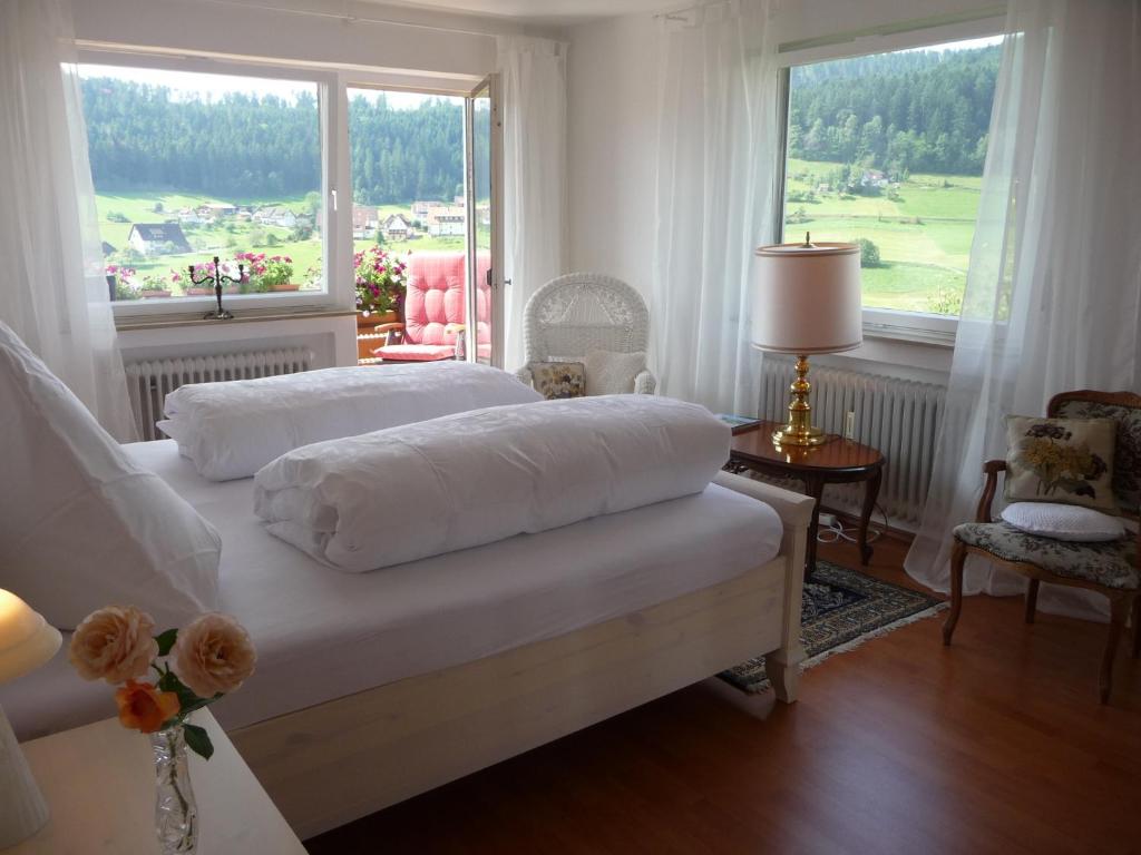 ein weißes Schlafzimmer mit einem Bett und einem großen Fenster in der Unterkunft Schwarzwald-Ferienwohnungen Begert in Baiersbronn