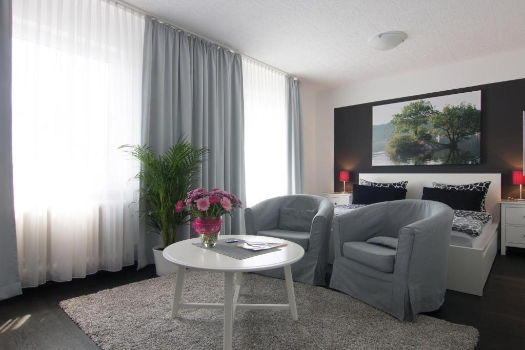 ein Wohnzimmer mit einem Sofa, Stühlen und einem Tisch in der Unterkunft Hotel Pension Haus Talblick Edersee in Hemfurth-Edersee