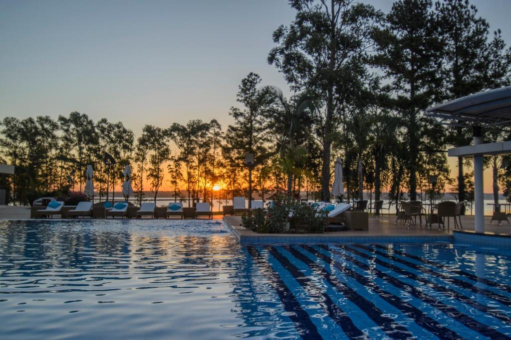 una piscina en un hotel con sillas y árboles en Awa Resort Hotel, en Encarnación