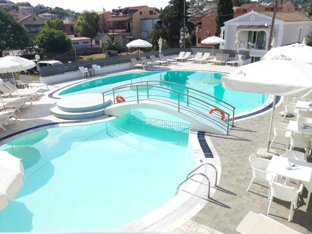 a large swimming pool with chairs and umbrellas at Kalimera Apartments in Kassiopi