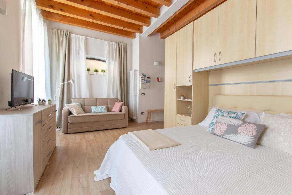 um quarto com uma cama branca e um sofá em Foresteria della Corte em Como