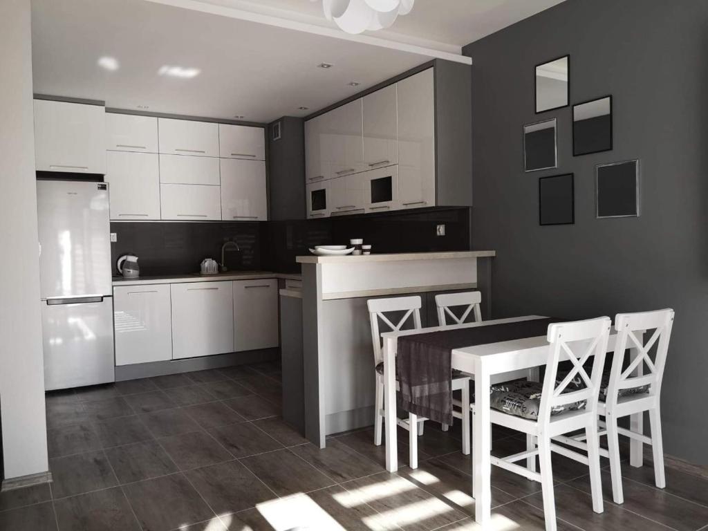uma cozinha com armários brancos e uma mesa e cadeiras em Golden Mazury Apartament em Giżycko