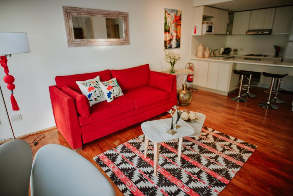 a living room with a red couch and a rug at Ribera de Pipo Cálido departamento para tu estancia in Ushuaia