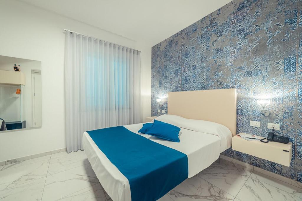 a bedroom with a large bed with a blue accent wall at Nautilus Hotel in Giardini Naxos