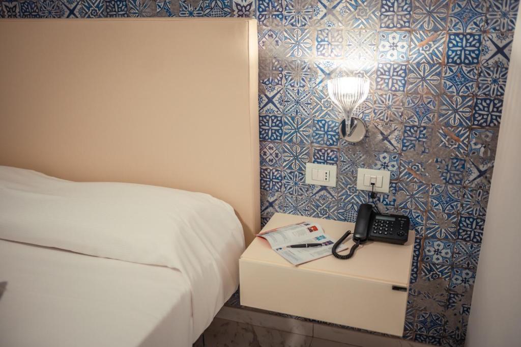 a bedroom with a bed and a phone on a night stand at Nautilus Hotel in Giardini Naxos