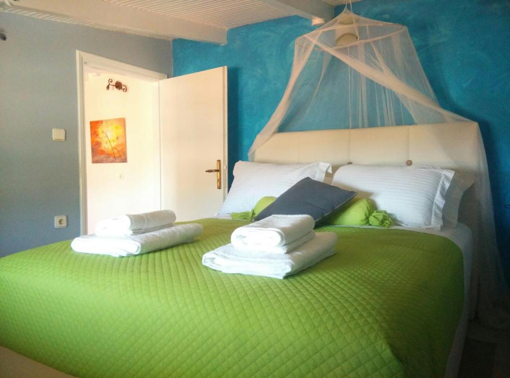 a bedroom with a green bed with pillows on it at Poseidon Apartments in Skala Kefalonias